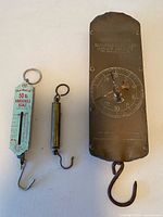 Three hanging spring balance scales laid out