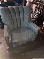 Front angled view of green channel-back armchair with carved wood arms