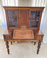 Front view of walnut secretary desk showing hutch, drawers, drop front and legs