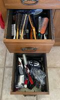 Two drawers filled with multiple hairbrushes and combs