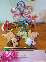 Overview of entire lot on table including plush toys, whistles, pinwheels, toy cars, figurine and accessories