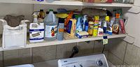 Shelf of assorted cleaning products above washer