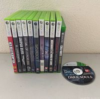 Group shot of eleven cased games lined upright plus loose Dark Souls disc