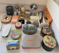 Group shot of entire lot on countertop showing tins, sprays, mirrors, compacts, combs