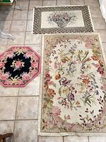 Overview showing three rugs: large floral, basket design, pink octagonal