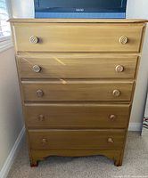 Front view of five-drawer wood dresser