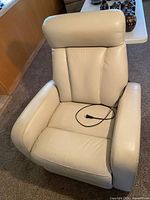 Front view of ivory power swivel glider recliner showing overall design and attached power cord