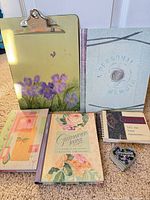 Group shot of clipboard, four journals, heart tin