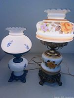 Both hurricane lamps side by side lit to show size difference and illumination