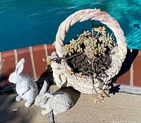 Planter with succulents beside two rabbit statues by pool