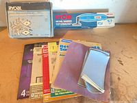 Lot overview with boxed sander, boxed mounting kit and stack of sandpaper