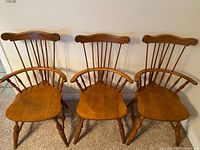 Front view of three matching maple comb-back arm chairs