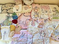All embroidered pieces and crochet caps laid out on bed