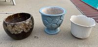 Group shot of three ceramic planters on poolside concrete