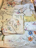 Overview of stacked vintage embroidered linens on bed