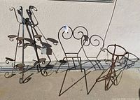 All three wrought iron plant stands lined up against wall