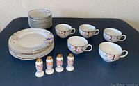Full lot showing stacked plates, cups, and four miniature shakers