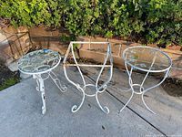 Three white wrought iron side tables, two with glass tops, one without