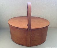 Full view of oval lidded basket with swing handle