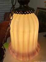 Illuminated ribbed opalescent shade showing color gradient and metal chain