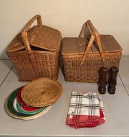 two wicker picnic baskets, stack of plates, wicker lid, napkins, grinders