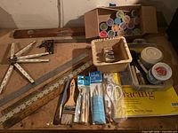 Group shot of rulers, level, square, tracing pad, brushes, paints and other supplies on workbench
