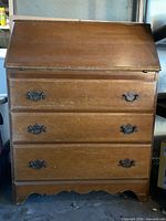 Front view with drop-front closed showing three drawers and hardware