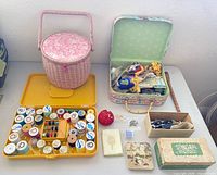 Overview showing wicker basket, floral sewing box, thread organizer, pin cushion, needle case, tin, Singer box, fasteners box, and small bead materials