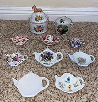 Group shot of both sugar bowls and eight tea bag holders on carpet