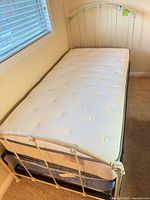 Overall view of metal twin bed with top mattress in place