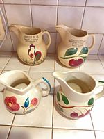 Group of four Watt pottery pitchers on tile counter
