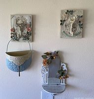 Two floral hook plaques and small mirror mounted on wall