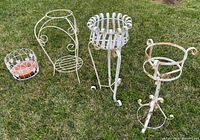 Group view of four white metal plant stands on grass