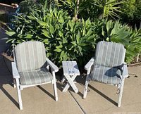 Two distressed white wood chairs with striped cushions flanking small matching table
