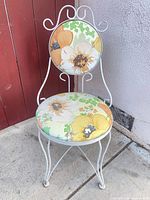 Full view of white wrought iron chair with floral vinyl upholstery