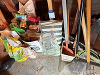 Group of garden tools, bags of fertilizer and chair cover