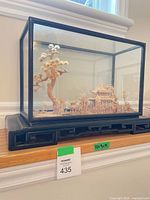 Full view of glass-encased carved landscape diorama on black base