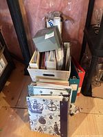 Stacked crate containing albums, binders, gray box, visible nautical binder front