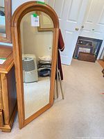 Full view of arched wood floor mirror leaning against wall
