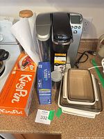 Overall lot with Keurig coffee maker, Brita box, reusable filter, storage containers, paper towel holder, KingPin box visible