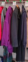 Row of hanging coats showing purple and navy coats in lot