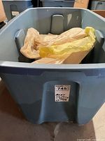 large plastic tote containing bagged baby clothing and blankets