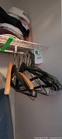Group of mixed wood, plastic and metal wire adult hangers hanging below shelf