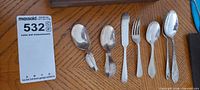 Six pieces of flatware laid out: spoons, fork, spreader, tongs