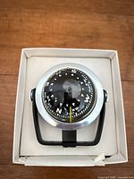 Top view of compass showing dial, bezel and bracket inside box