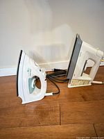 Side view of both irons showing overall form, cords, heel rests