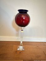 Full view of candle holder showing red globe, blue rim, clear stem and base