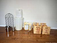 Group shot showing all items lined against wall: rack, ice buckets, trash bin, jerry can, distiller, crates