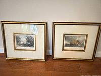 Both framed engravings standing against wall