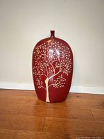 Front view of red ceramic vase with beige tree design
